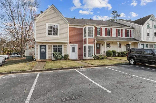 a view of a white house with a large space next to a road