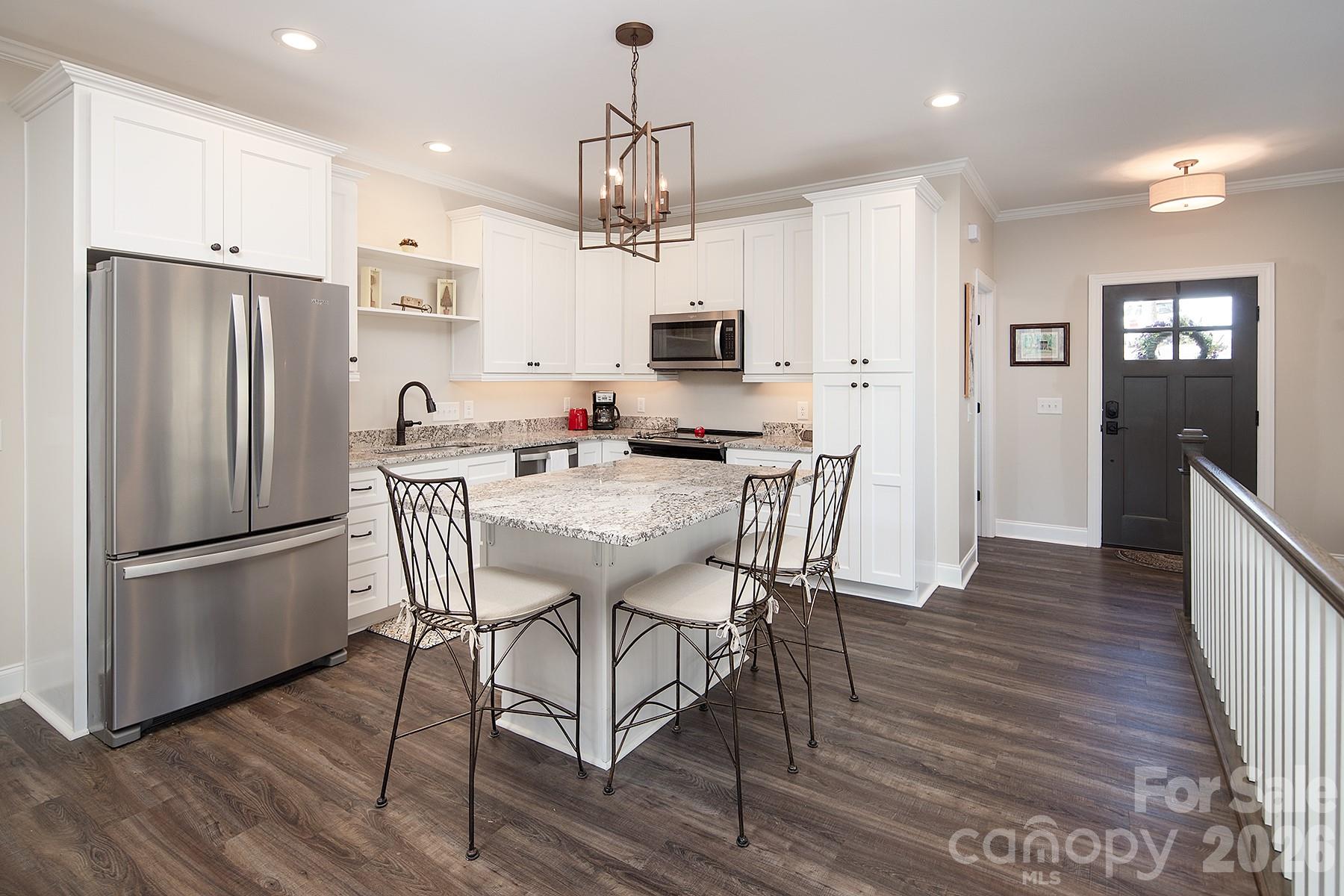 689 Emerald Shores Road Mount Gilead, NC 27306 - Photo 11 of 46 a kitchen with stainless steel appliances a dining table chairs refrigerator and microwave