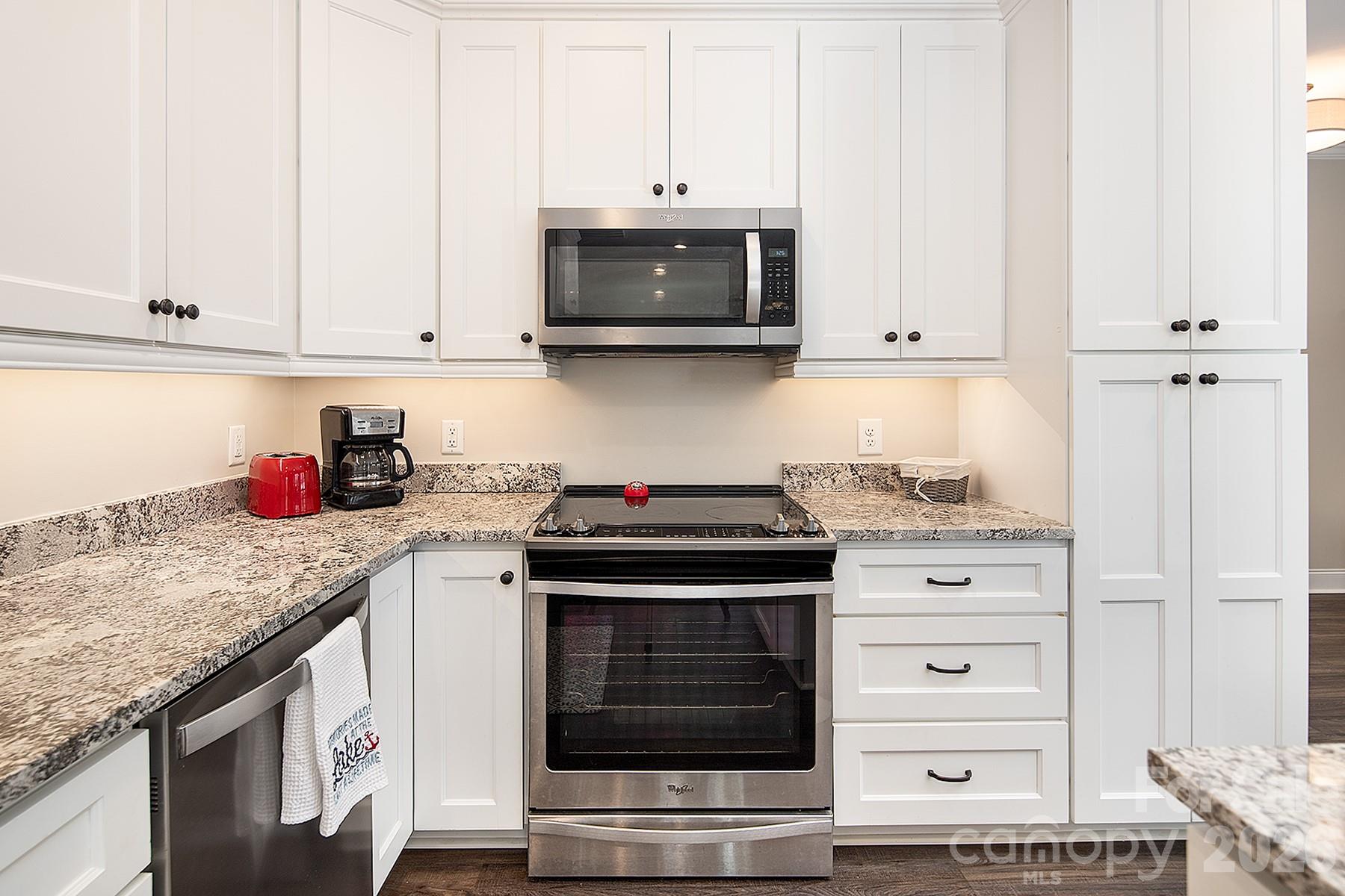 689 Emerald Shores Road Mount Gilead, NC 27306 - Photo 13 of 46 a kitchen with granite countertop white cabinets and stainless steel appliances