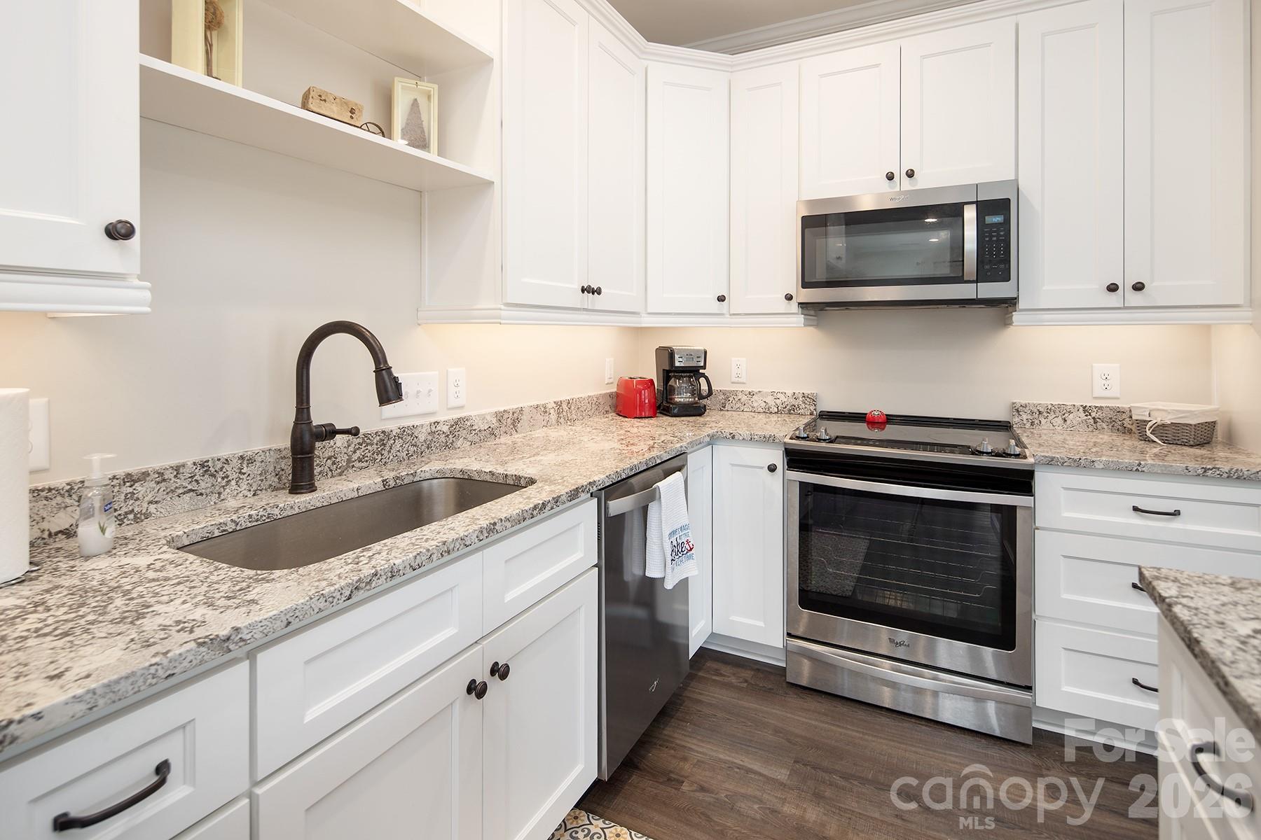 689 Emerald Shores Road Mount Gilead, NC 27306 - Photo 14 of 46 a kitchen with stainless steel appliances granite countertop a sink a stove a microwave and cabinets