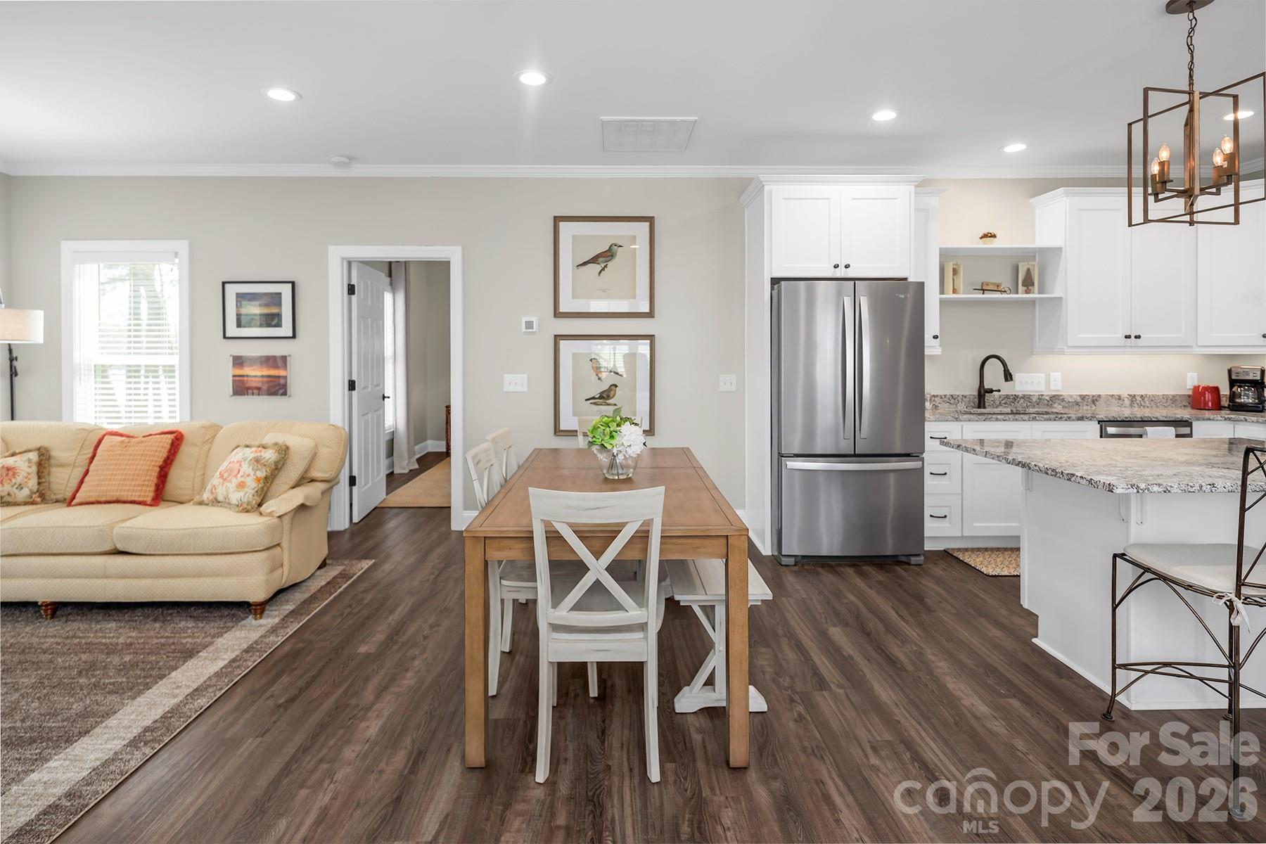 689 Emerald Shores Road Mount Gilead, NC 27306 - Photo 16 of 46 a kitchen with stainless steel appliances a refrigerator a stove a dining table and chairs with wooden floor
