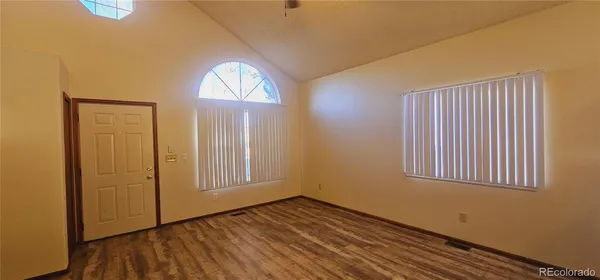 an empty room with wooden floor closet and windows