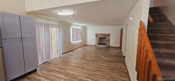 a view of an empty room with wooden floor and stairs