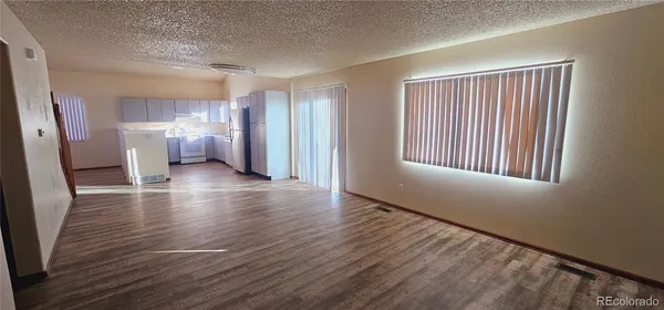 a view of a room with wooden floor kitchen and windows