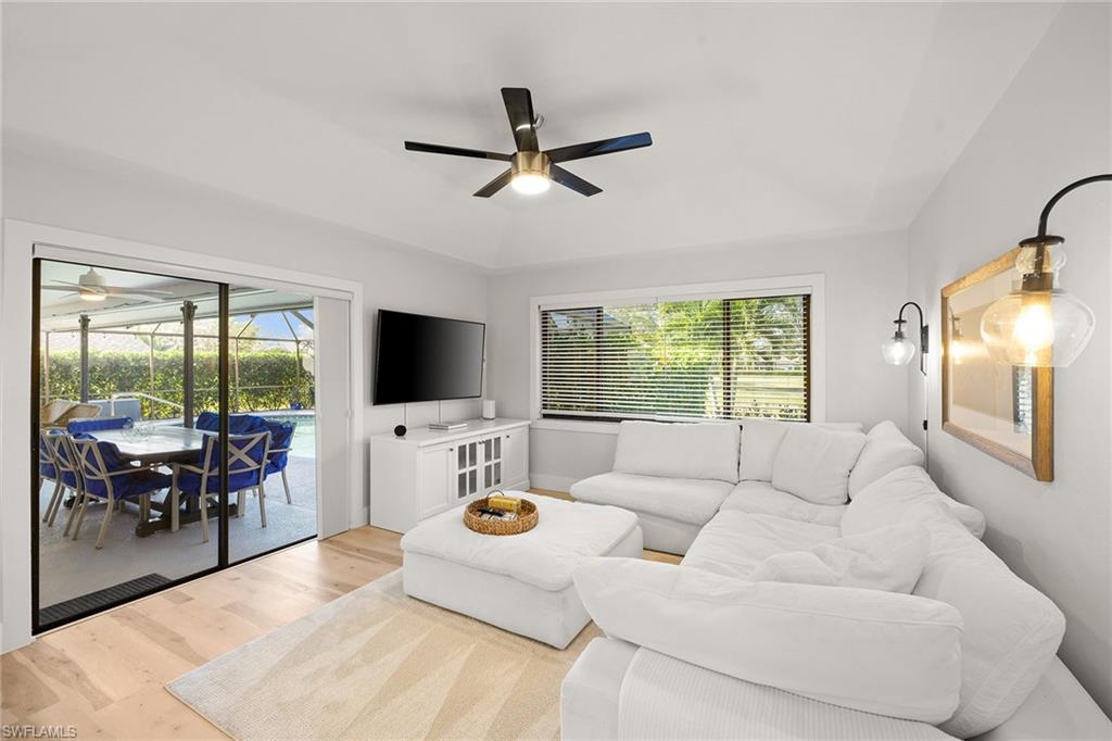 130 Torrey Pines Point Naples, FL 34113 - Photo 12 of 44 a living room with furniture floor to ceiling window hardwood floor and a flat screen tv