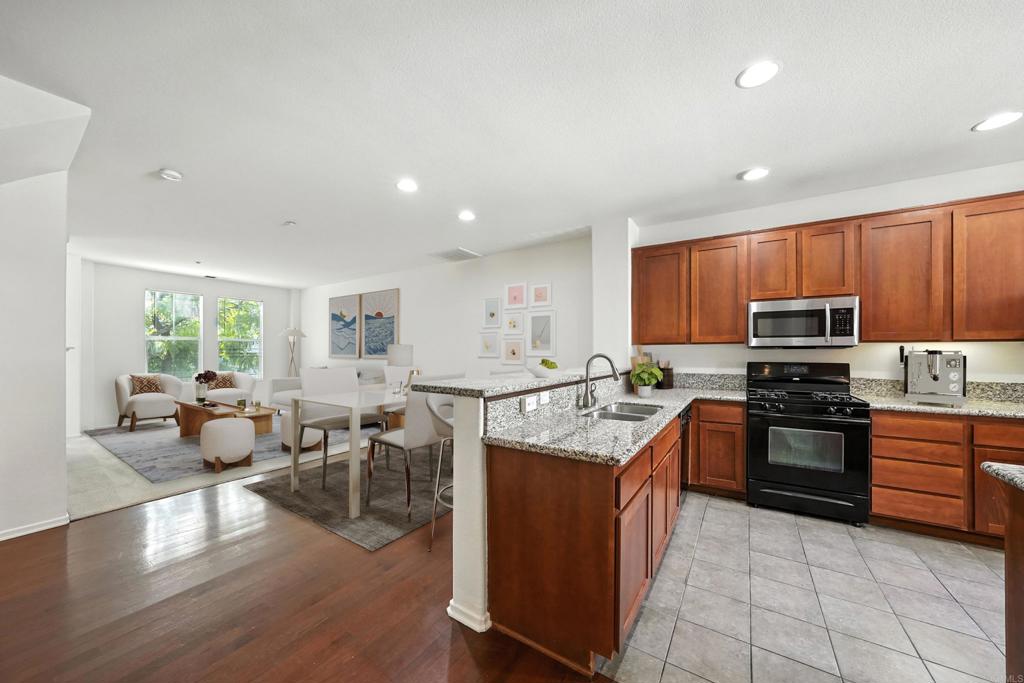 1569 Hackberry Place Chula Vista, CA 91915 - Photo 5 of 23 a kitchen with stainless steel appliances granite countertop a stove top oven a sink dishwasher a dining table and chairs with wooden floor