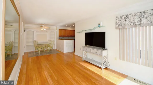 a living room with a flat screen tv on dresser and a table