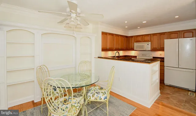 a kitchen with stainless steel appliances granite countertop a refrigerator a microwave oven a sink with island and chairs