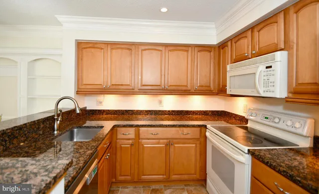 a kitchen with granite countertop stainless steel appliances stove top oven and cabinets