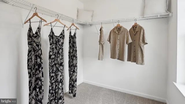 a view of walk in closet with clothes and shoes