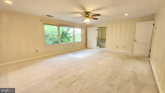 an empty room with windows and a ceiling fan