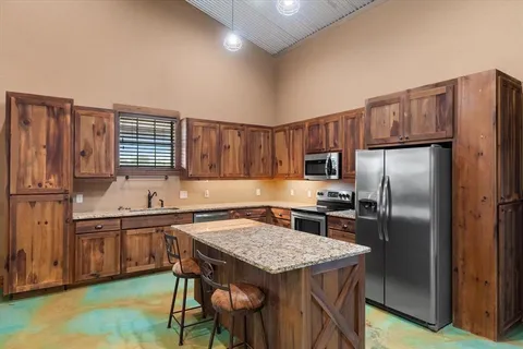 a kitchen with kitchen island a counter space a sink appliances and cabinets
