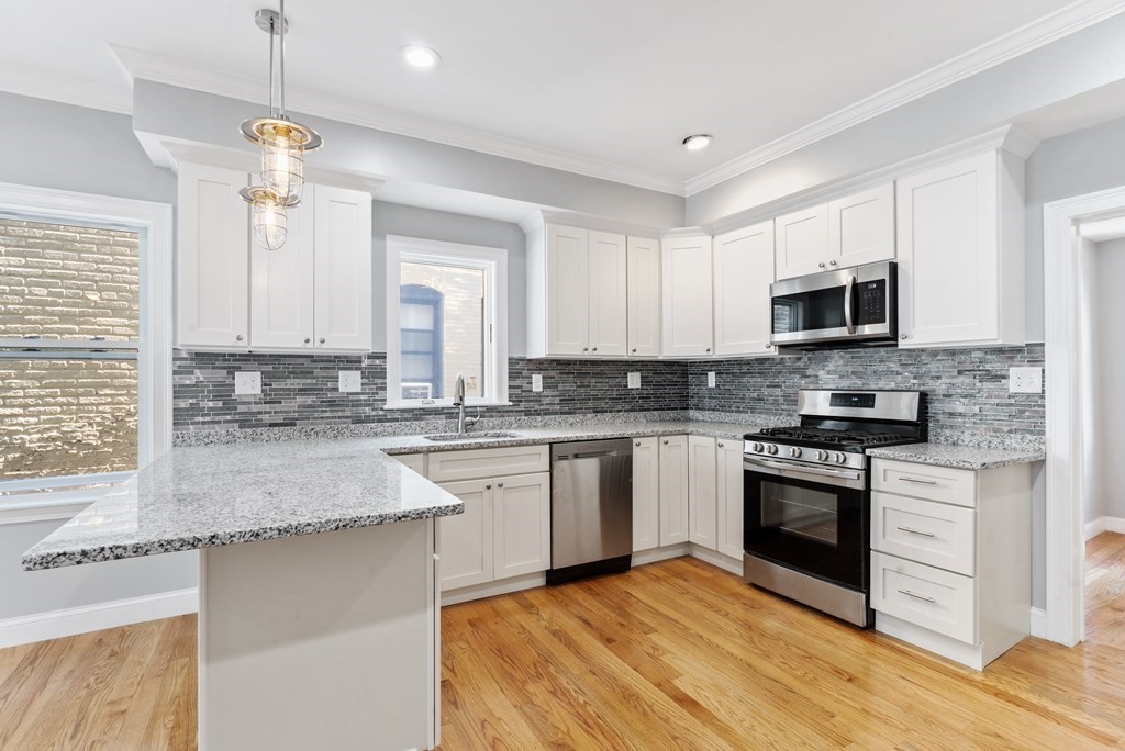 9 Wales Street, Unit 2 Boston, MA 02124 - Photo 9 of 15 a kitchen with granite countertop a stove a sink and a microwave
