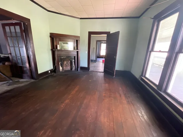 a view of an empty room with wooden floor and a window