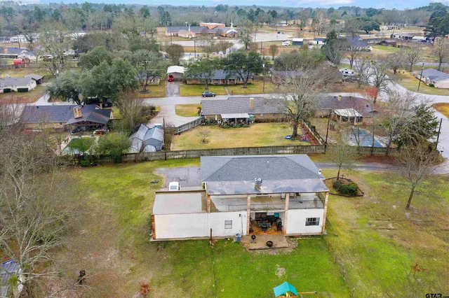a view of a white house with a yard potted plants and a large tree