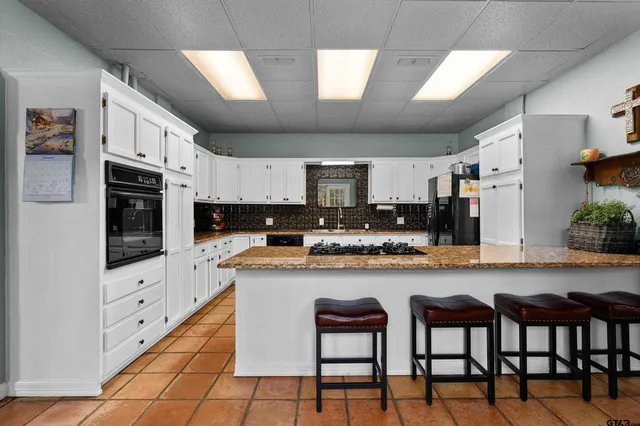 a kitchen with granite countertop a table chairs microwave and cabinets