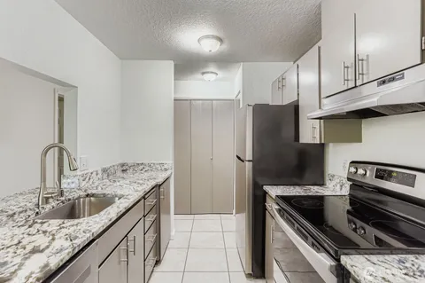 a kitchen with granite countertop a sink stove and refrigerator