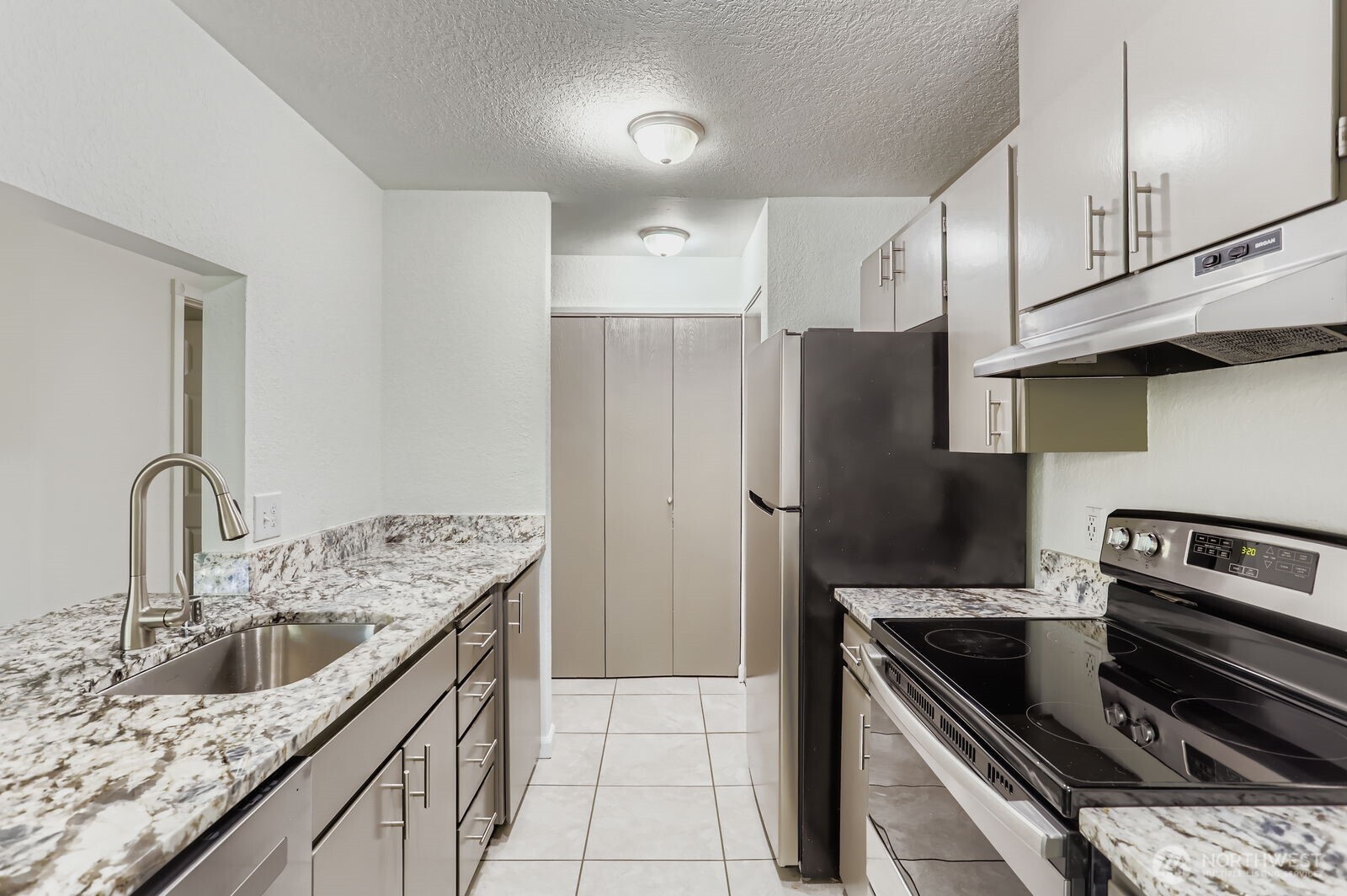 830 Kirkland Way, Unit 204 Kirkland, WA 98033 - Photo 13 of 27 a kitchen with granite countertop a sink stove and refrigerator