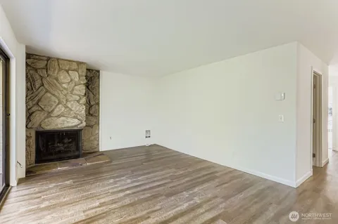 a view of an empty room with wooden floor and a fireplace