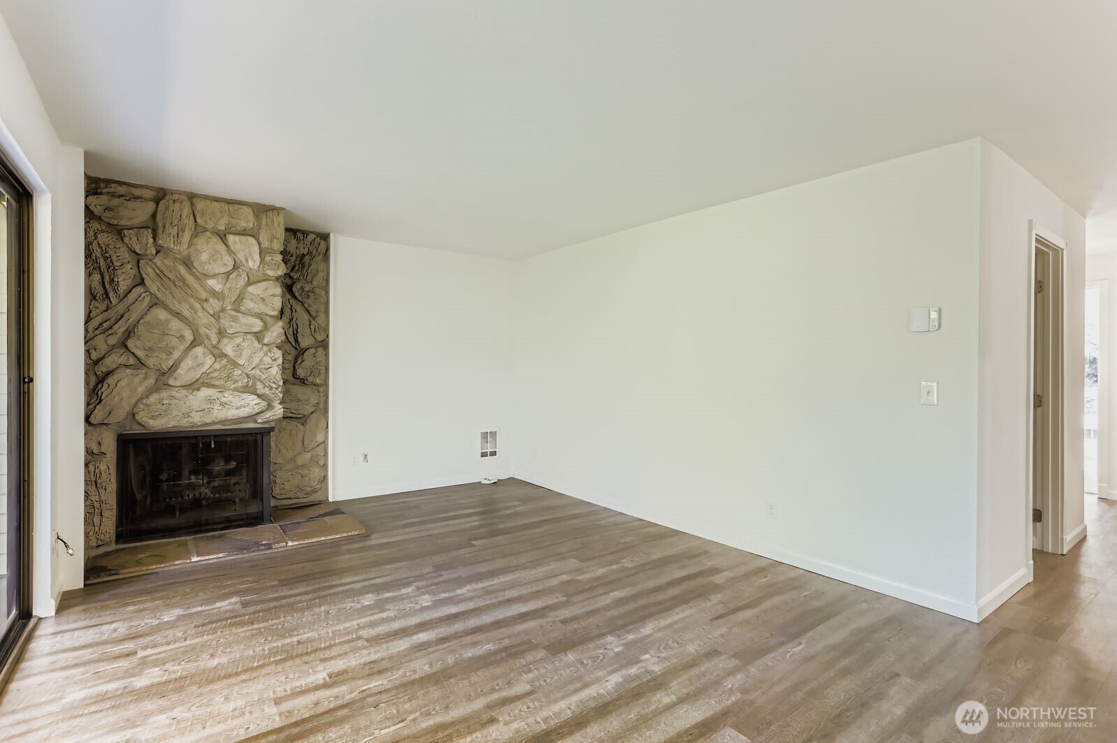 830 Kirkland Way, Unit 204 Kirkland, WA 98033 - Photo 5 of 27 a view of an empty room with wooden floor and a fireplace