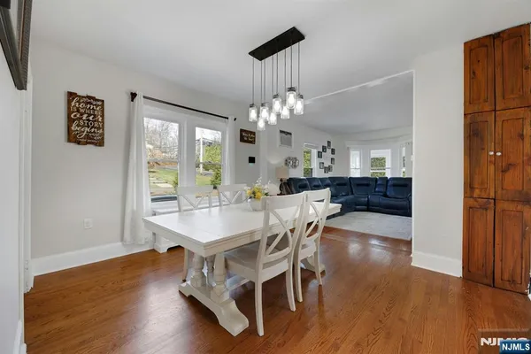a dining room with wooden floor a chandelier a wooden table and chairs