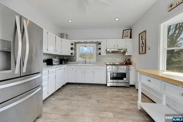 a kitchen with kitchen island white cabinets and stainless steel appliances