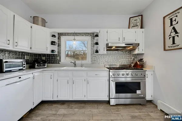 a kitchen with stainless steel appliances granite countertop a stove and white cabinets