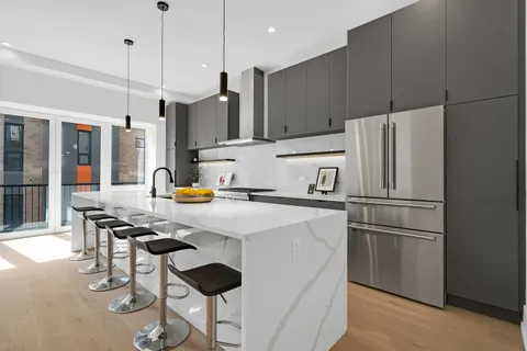 a kitchen with stainless steel appliances a refrigerator a sink a stove a dining table and chairs