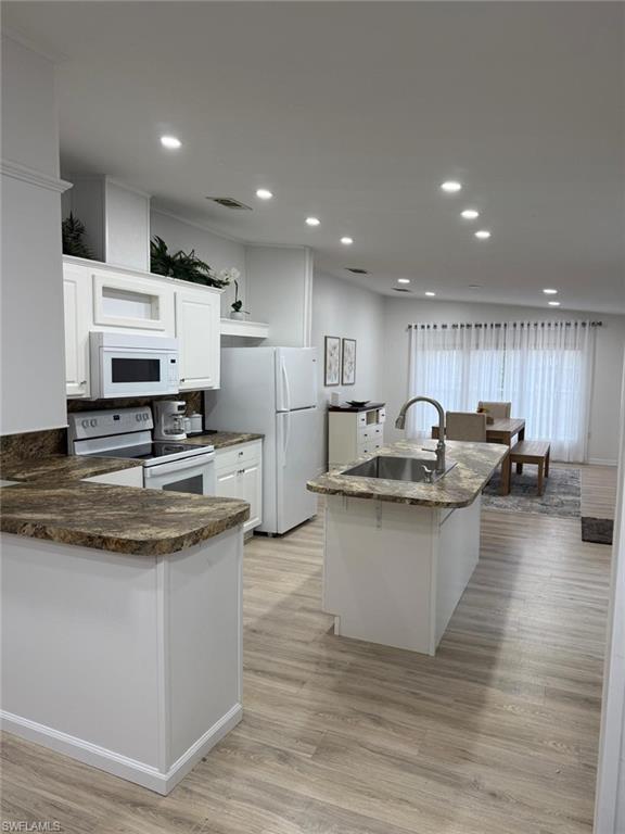 a kitchen with stainless steel appliances granite countertop a stove a sink dishwasher a refrigerator and white cabinets with wooden floor