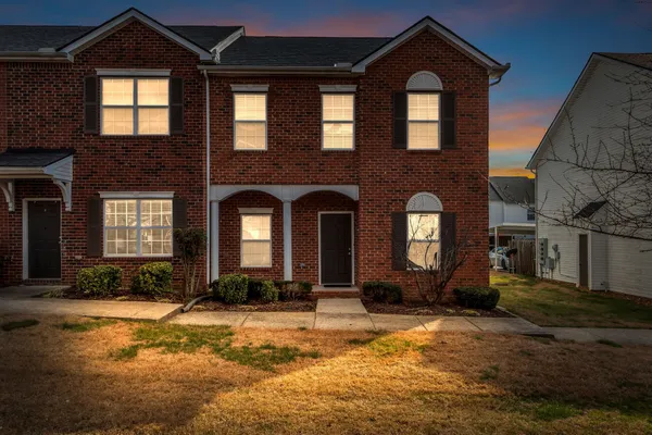 a view of a brick house with large windows and a yard
