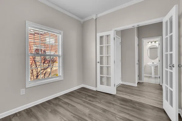 a view of an empty room with wooden floor and a window