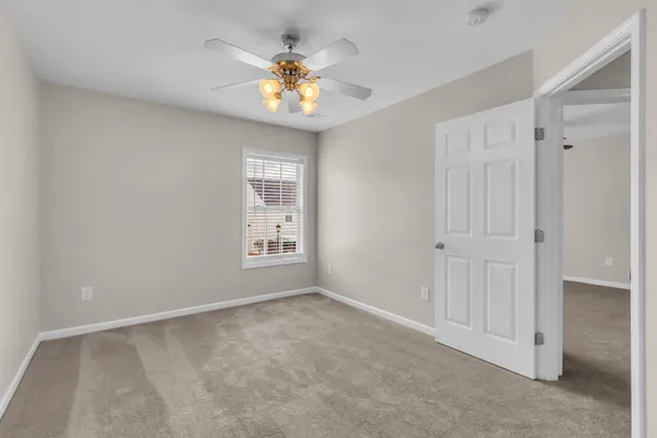 an empty room with windows and chandelier fan