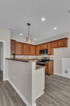 a kitchen with stainless steel appliances granite countertop a refrigerator a sink dishwasher a s stove top oven a dining table and chairs with wooden floor