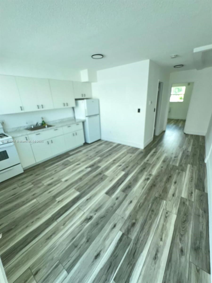 524 Washington Avenue, Unit 310 Miami Beach, FL 33139 - Photo 1 of 6 a view of a kitchen with kitchen island white cabinets and wooden floor