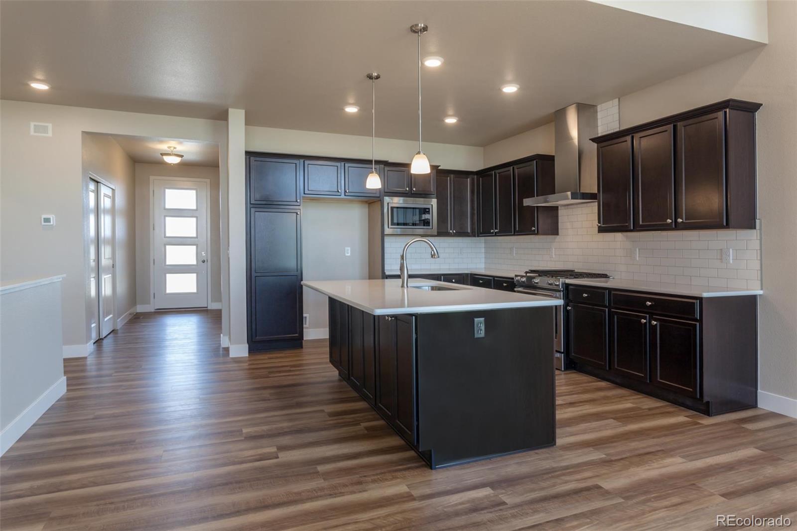 6768 Castello Street Timnath, CO 80547 - Photo 11 of 38 a kitchen with wooden floors and black appliances