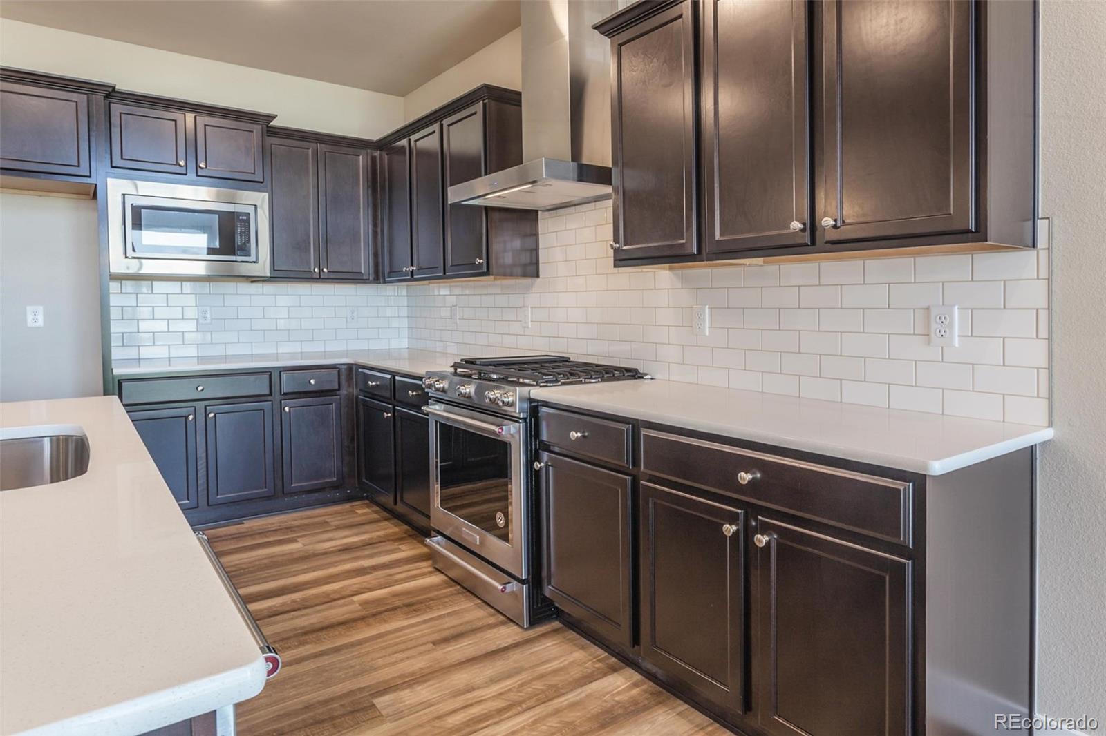 6768 Castello Street Timnath, CO 80547 - Photo 36 of 38 a kitchen with stainless steel appliances granite countertop a sink stove and cabinets