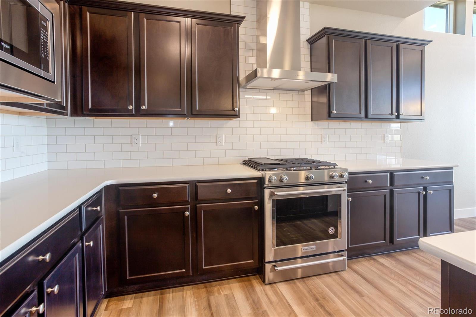 6768 Castello Street Timnath, CO 80547 - Photo 4 of 38 a kitchen with stainless steel appliances wooden cabinets and a stove top oven