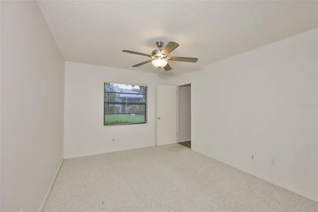 an empty room with a window and ceiling fan