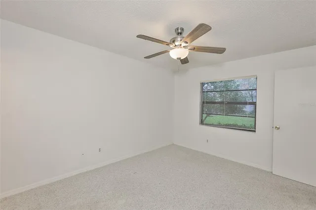 an empty room with fan closet and a ceiling fan