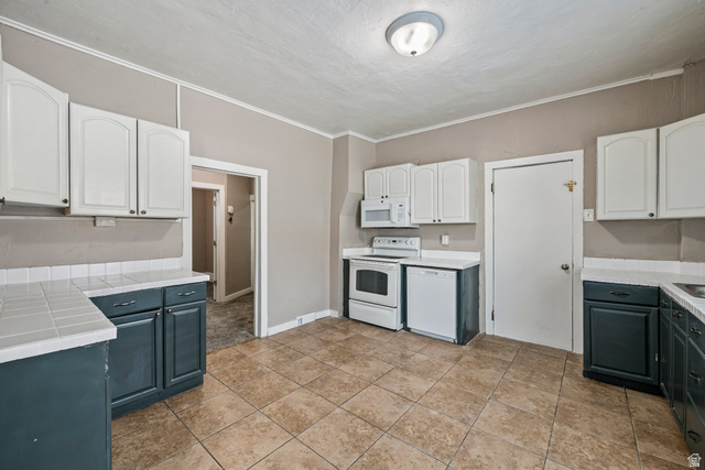 75 600 West Provo, UT 84601 - Photo 4 of 26 Kitchen featuring tiled flooring, two-tone cabinetry with white upper and dark lower cabinets, a white tile backsplash, and a white appliance suite including a range, microwave, and dishwasher