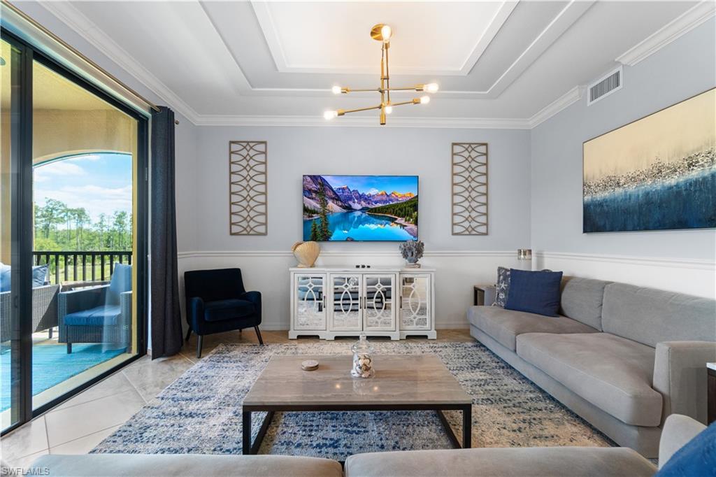 9590 Trevi Court, Unit 5337 Naples, FL 34113 - Photo 1 of 14 a living room with furniture a chandelier and a large window