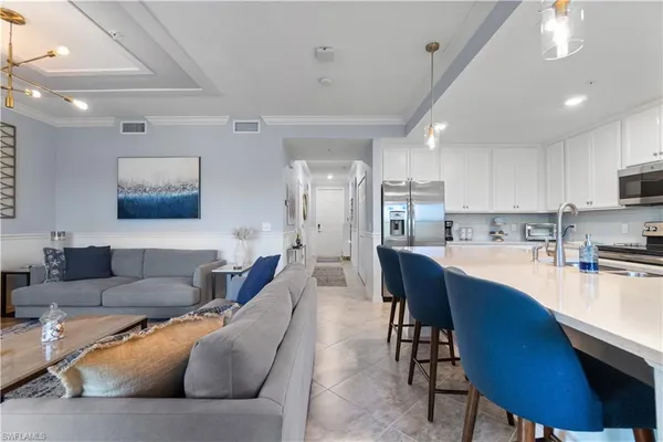 a living room filled with furniture and kitchen view