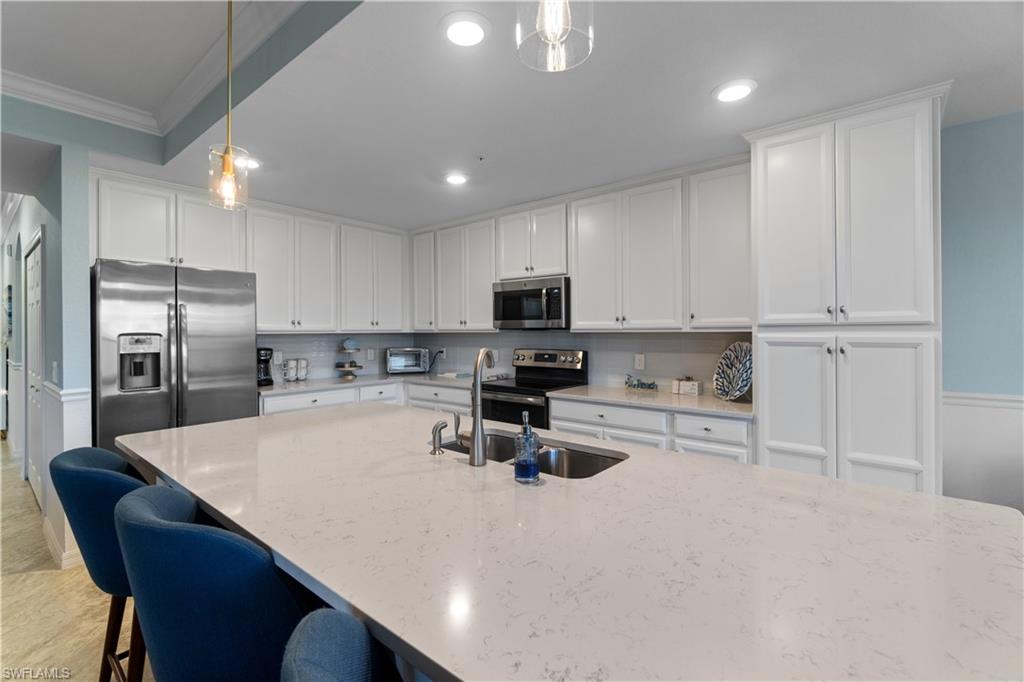 9590 Trevi Court, Unit 5337 Naples, FL 34113 - Photo 6 of 14 a kitchen with refrigerator a stove a sink cabinets and a counter top space