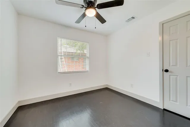 an empty room with a window and a ceiling fan