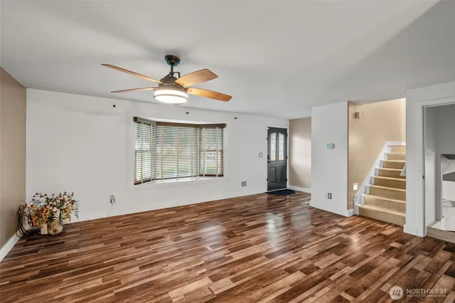 a view of an empty room with window and wooden floor