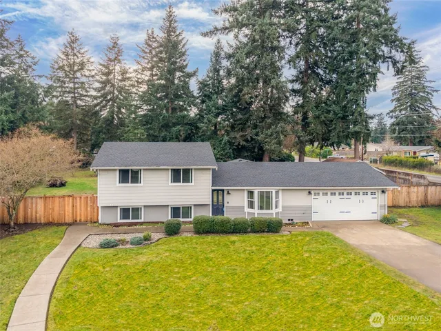 a view of a house with a big yard plants and large tree