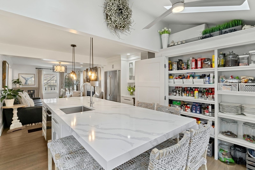 194 Merrymount Road Quincy, MA 02169 - Photo 10 of 32 a large white kitchen with kitchen island a refrigerator a stove a sink and a dining table with wooden floor
