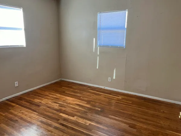 an empty room with wooden floor and windows