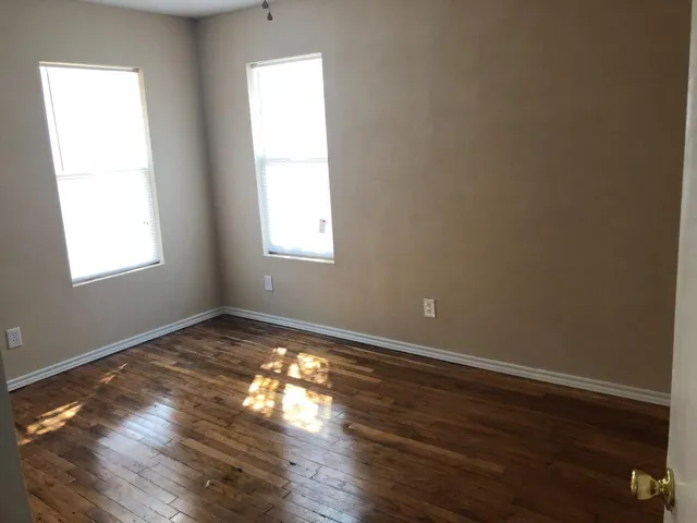 an empty room with wooden floor chandelier fan and windows