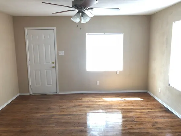 a view of a room with wooden floor and a ceiling fan